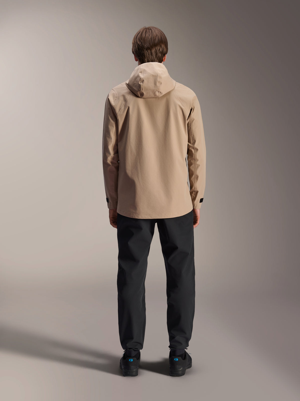 Alpinestars A-Dura Rain Jacket, Light Brown, back view showing hood and adjustable cuffs, worn with black pants, versatile all-weather MTB gear