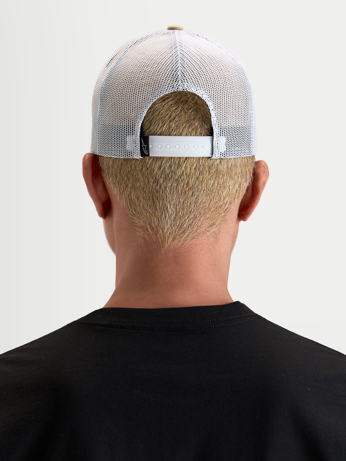 Alpinestars Casquette Cali 2.0, casquette trucker sportswear, kaki et blanche, vue de dos portée par un modèle, montrant la fermeture à pression réglable et le panneau arrière en maille respirante
