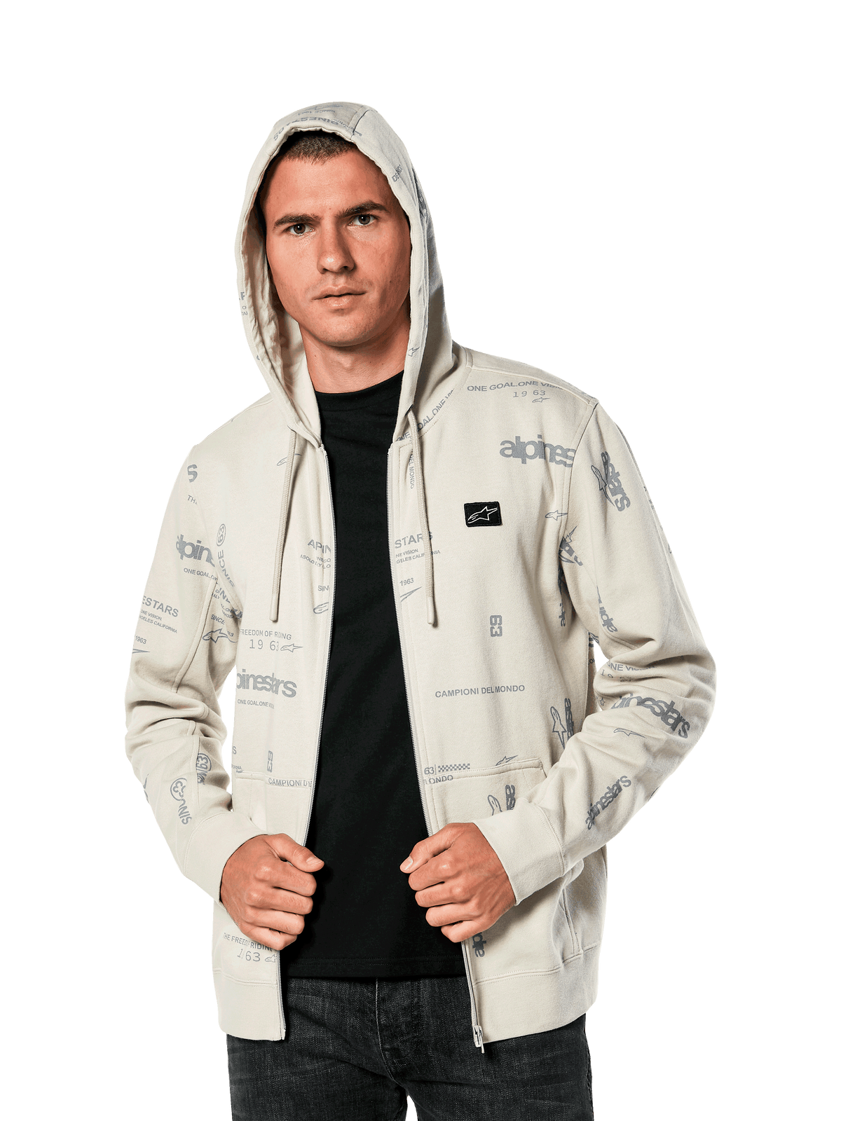 Alpinestars Plenitude Hoodie, casual sportswear, Off White zip-front fleece with all-over grey logo graphics, worn by a man with the hood up over a black shirt, featuring a small chest logo patch and kangaroo pocket