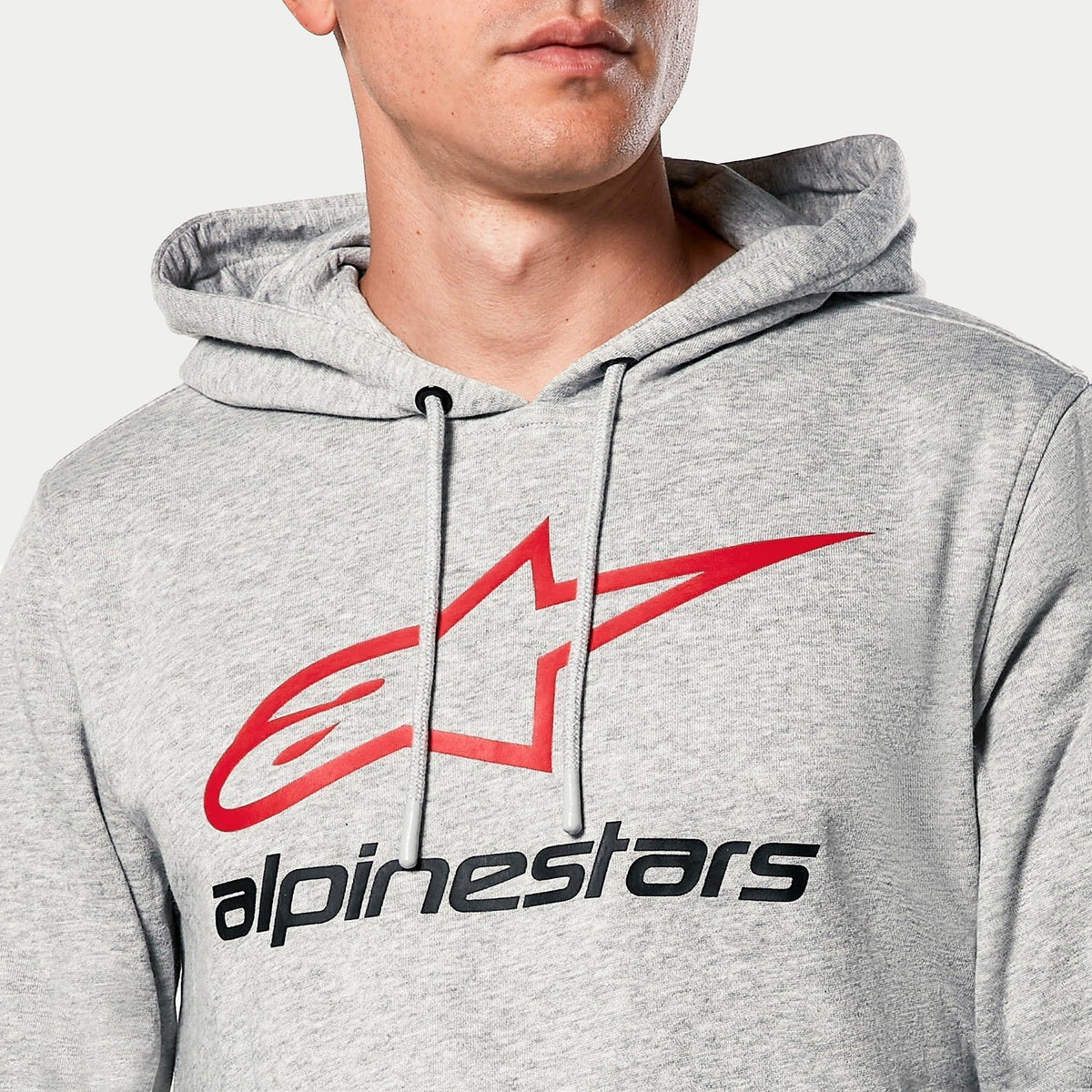 Sweat à capuche Alpinestars Always V3, gris chiné, gros plan sur la poitrine avec logo étoile rouge et lettrage Alpinestars noir, capuche doublée en jersey avec cordons gris, style sportswear décontracté