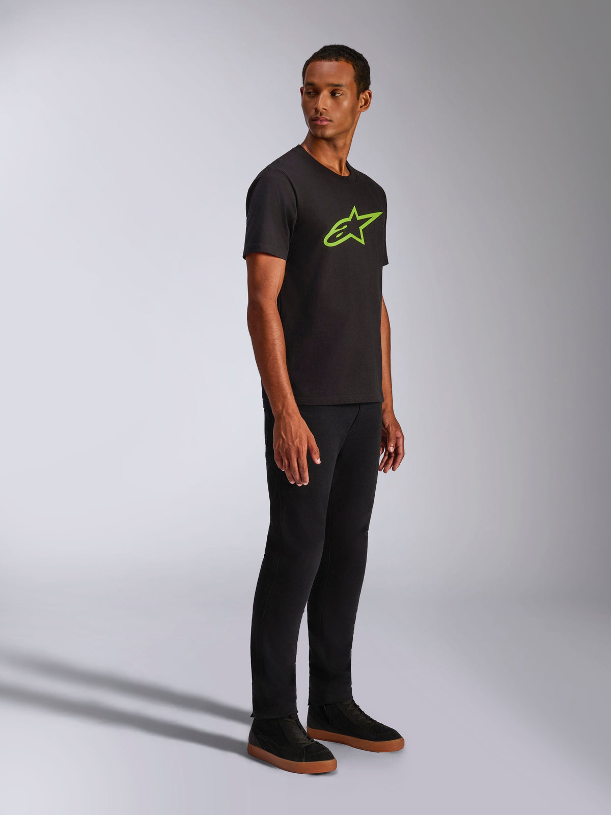 Alpinestars Ageless 2.0 CSF Tee, Short Sleeve T-Shirt, Black with Bright Green Alpinestars Logo, styled with black pants and sneakers, casual motorsport-inspired streetwear