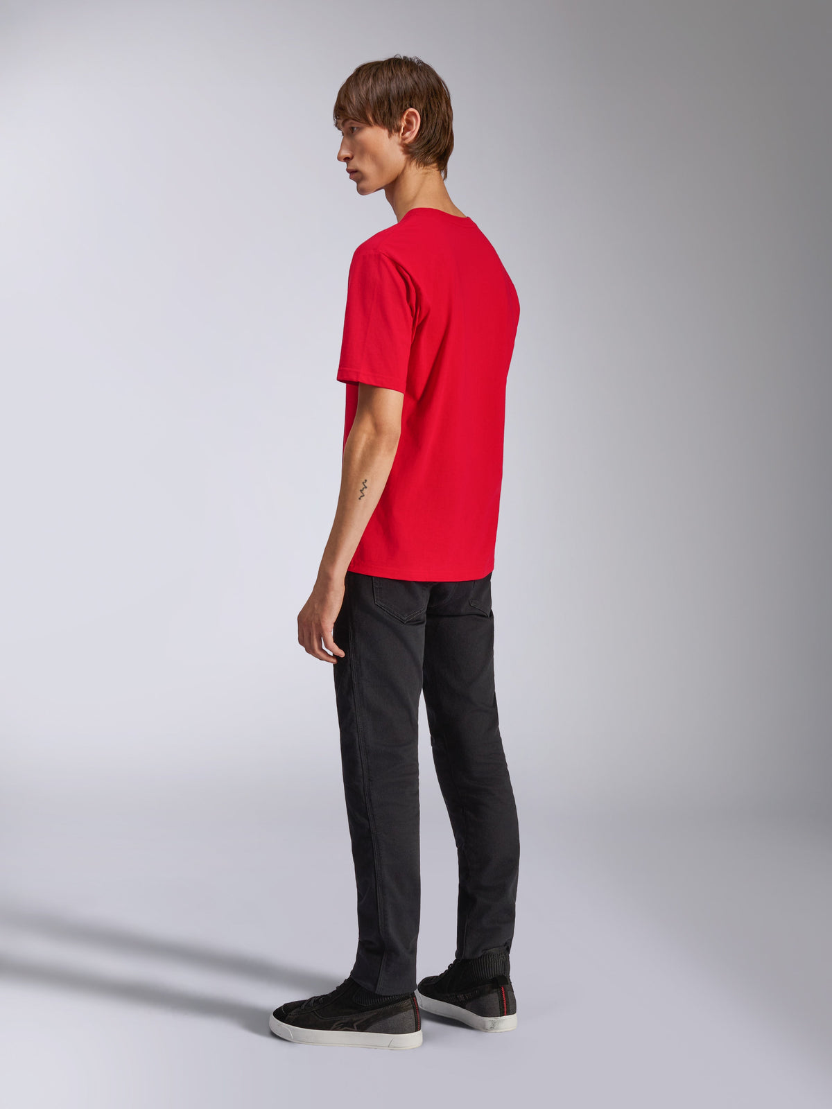 Alpinestars Ageless Shadow CSF Tee, t-shirt à manches courtes, rouge, vue de dos sur mannequin, porté avec un pantalon noir et des baskets, streetwear décontracté d'inspiration sports mécaniques