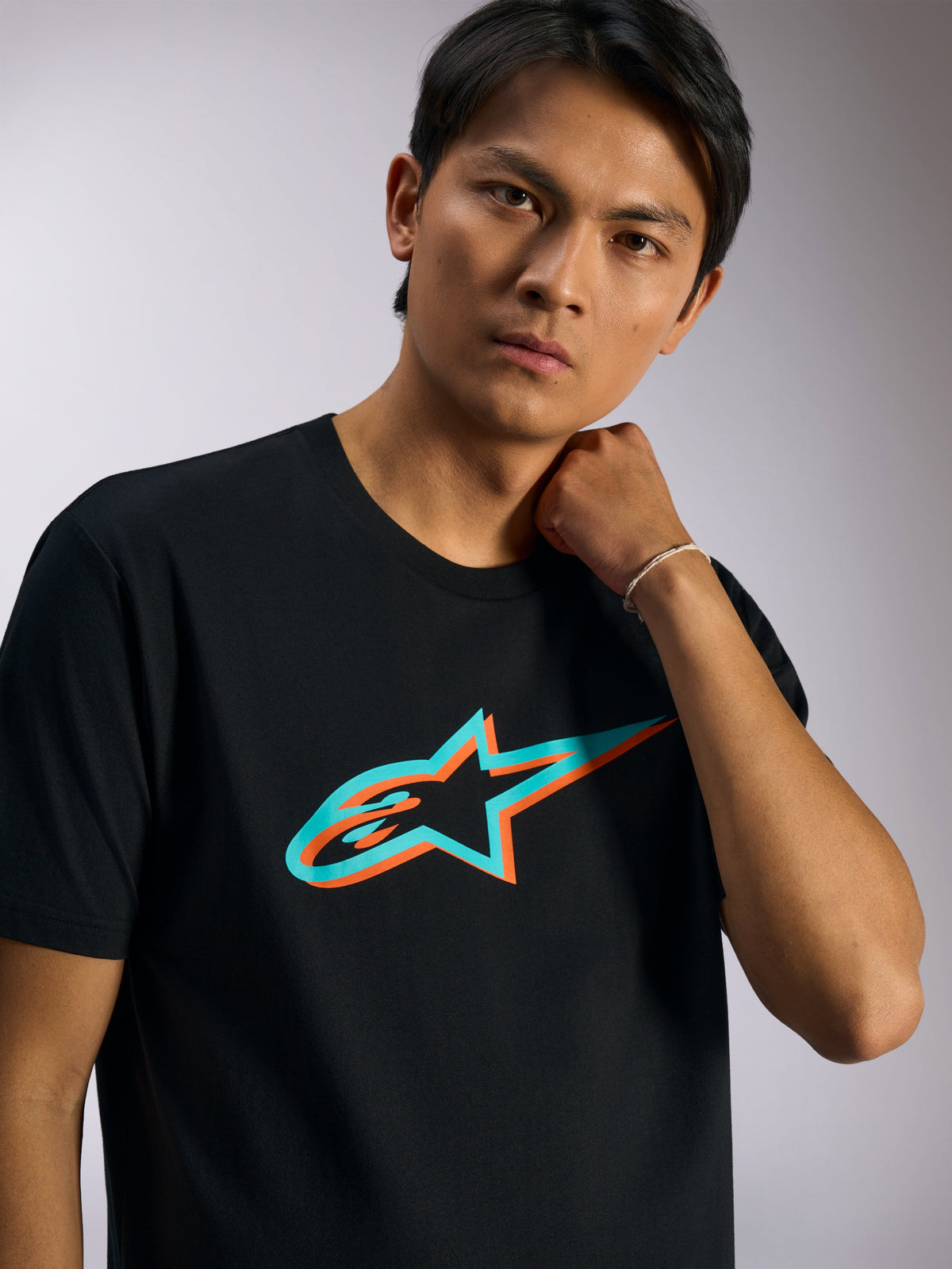 T-shirt Alpinestars Ageless Shadow CSF, t-shirt à manches courtes, noir avec logo Ageless ombré turquoise et orange, porté par un mannequin, vêtement streetwear décontracté inspiré du sport automobile