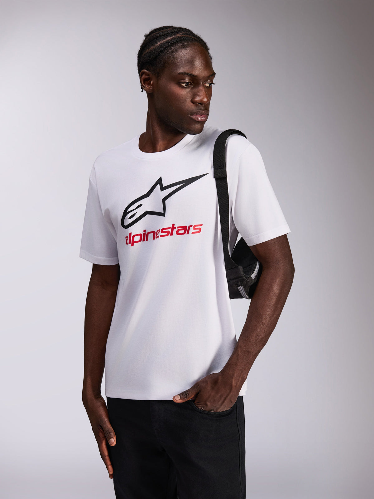 T-shirt Always 2.0 CSF Alpinestars, t-shirt à manches courtes, blanc, logo étoile noir et texte Alpinestars rouge, porté par un mannequin avec un sac bandoulière noir, sportswear décontracté
