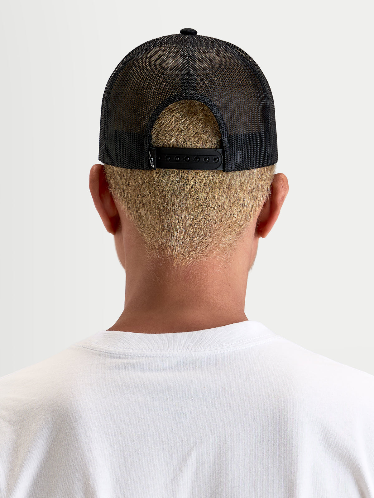 Casquette Trucker Heritage Patch d'Alpinestars, casquette casual en maille noire, vue de dos montrant la fermeture snapback réglable et la construction en maille polyester portée par un modèle