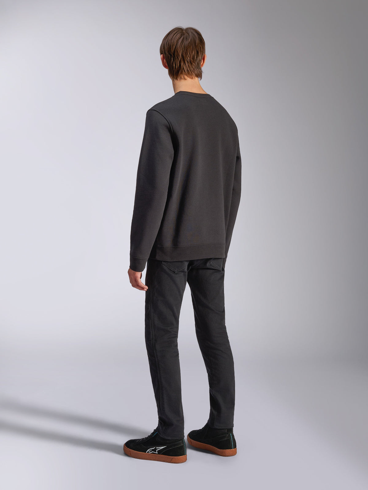 Alpinestars Positive Crew, sweatshirt noir, vue de dos sur mannequin, streetwear décontracté d'inspiration sport automobile, avec bord-côte aux poignets et à l'ourlet.