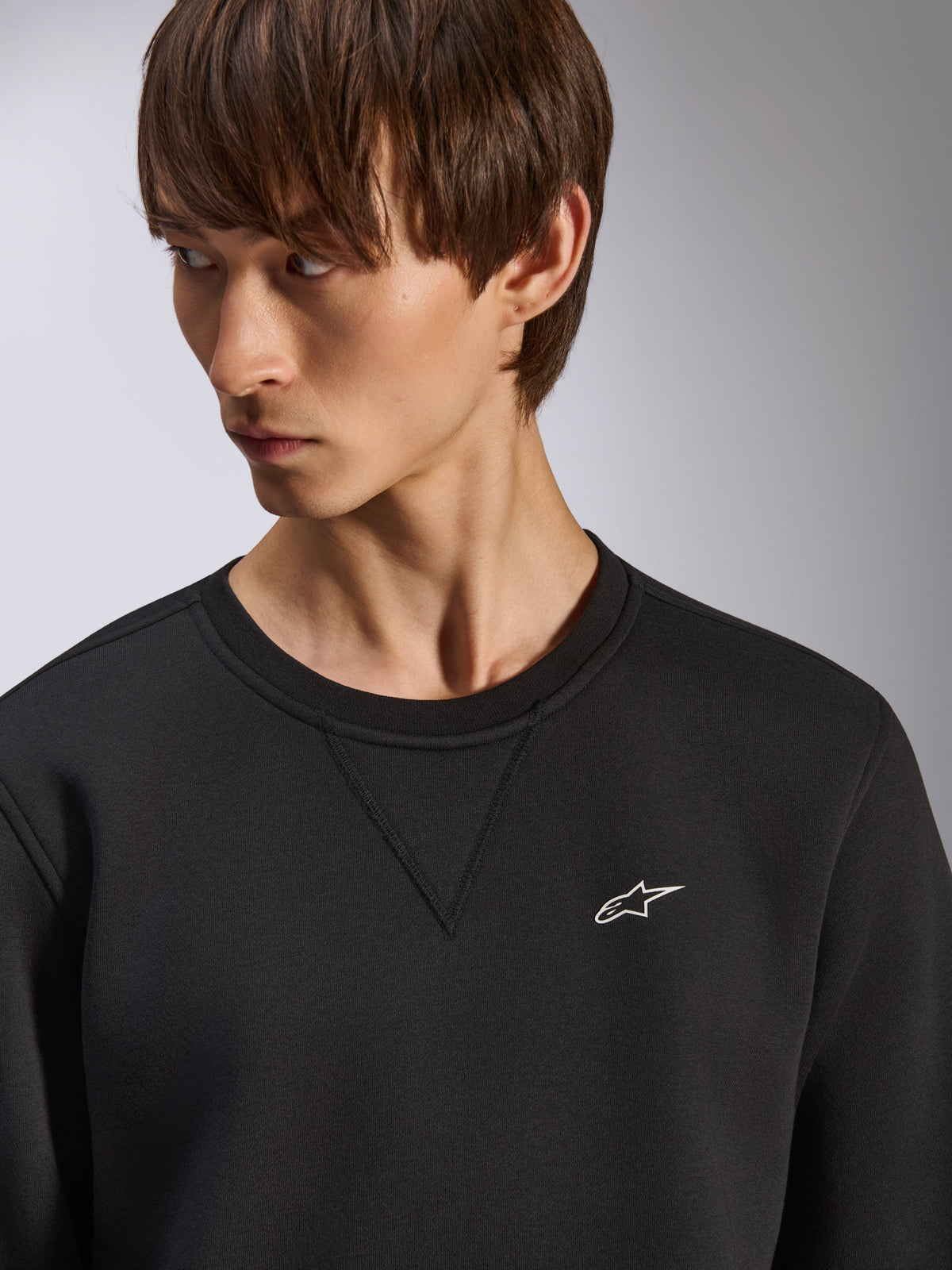 Sweat-shirt Alpinestars Positive Crew, col rond noir avec détail de couture en V au col, petit logo Alpinestars blanc sur la poitrine gauche, streetwear décontracté inspiré du sport automobile
