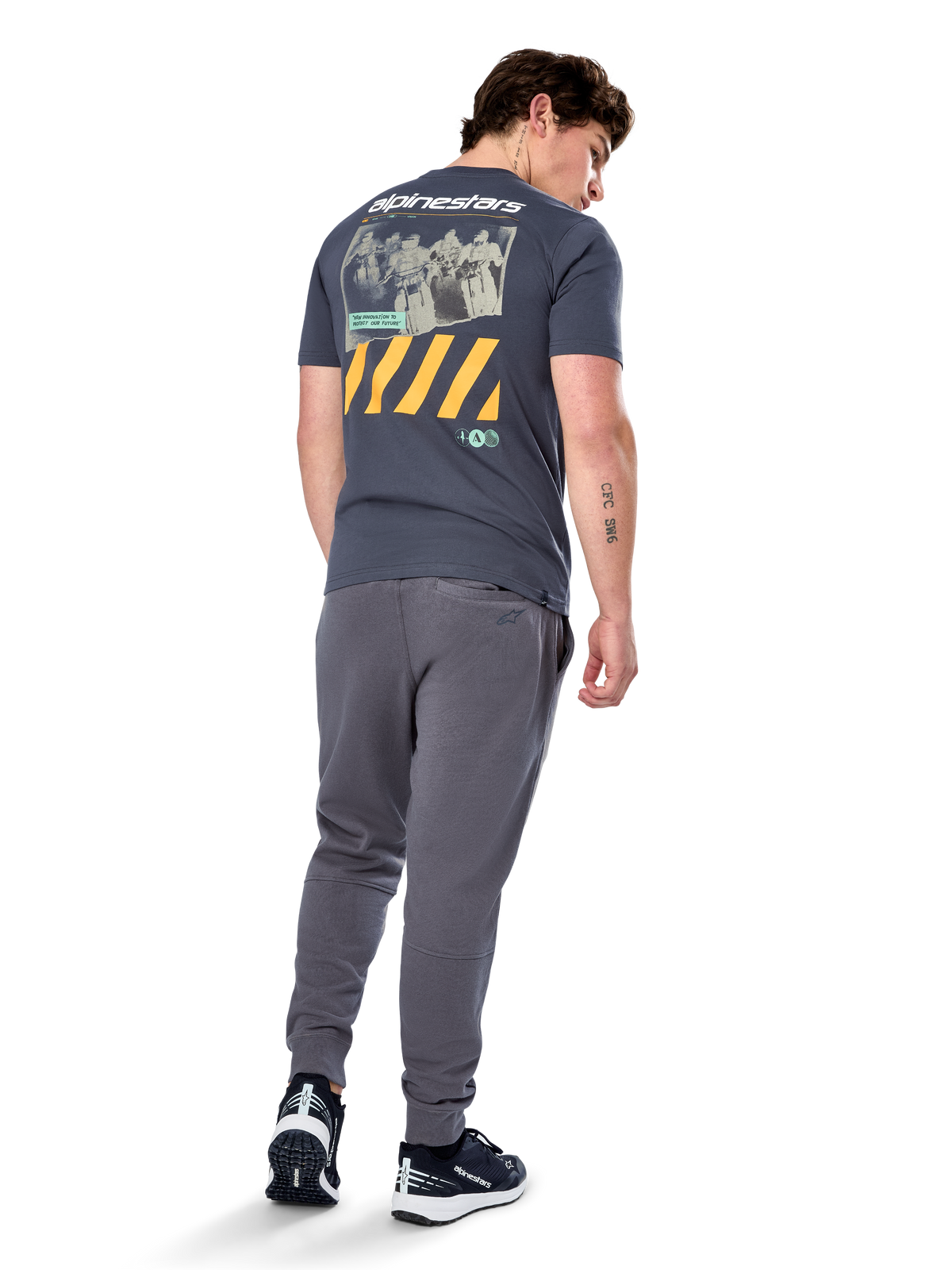 Alpinestars No Barrier CSF Tee, t-shirt à manches courtes, anthracite, vue de dos présentant un grand graphique photo vieilli avec des bandes diagonales jaunes et un logo blanc, streetwear décontracté inspiré du sport automobile