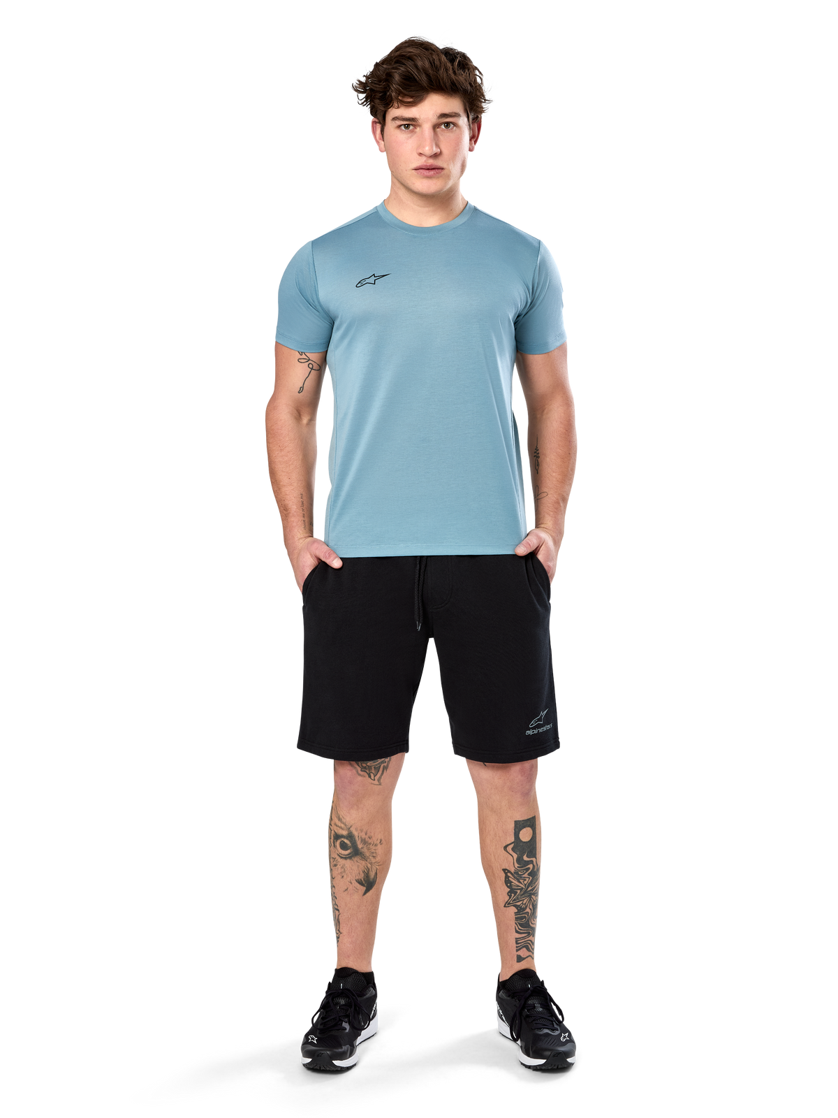 Alpinestars Point Performance Tee, t-shirt à manches courtes, bleu glacier, doté d'un petit logo noir à l'avant et d'un col rond, porté par un mannequin avec un short noir et des baskets noires, vêtement de sport décontracté évacuant l'humidité