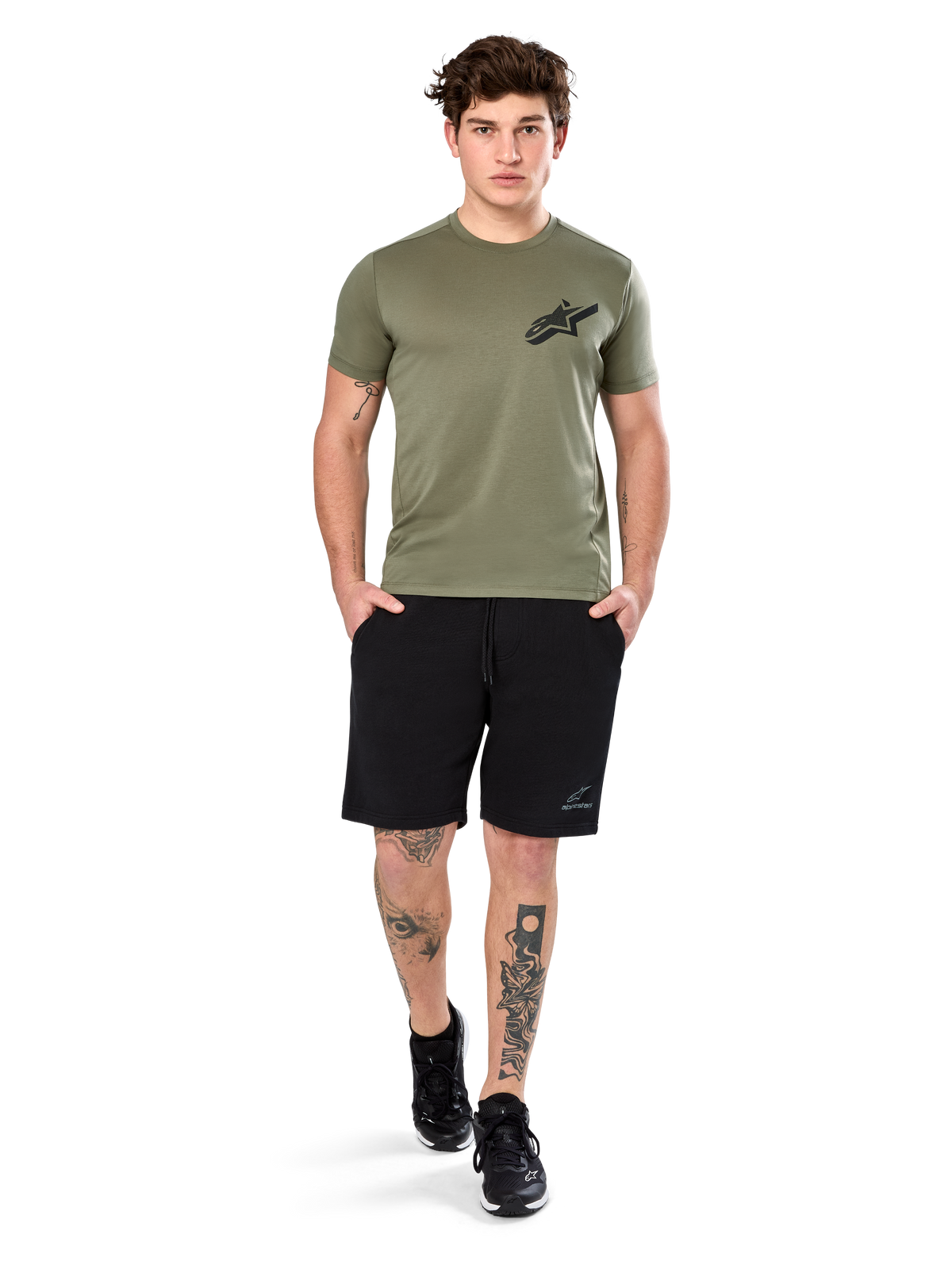 T-shirt Alpinestars Attrition Performance, t-shirt à manches courtes, vert clair, avec logo Astars noir sur la poitrine, porté avec un short de sport noir et des baskets noires, cliché lifestyle sportswear performance décontracté