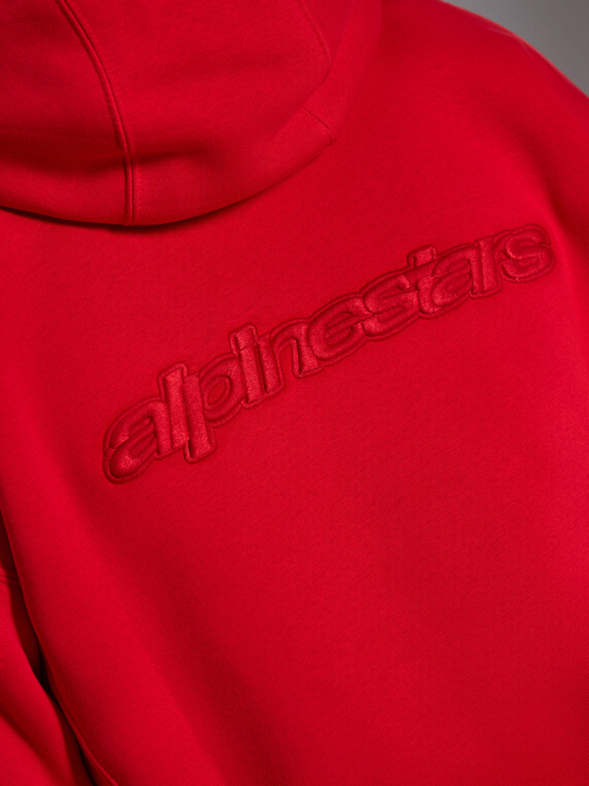 Sweat à capuche Alpinestars Emergent Oversized, rouge, gros plan du dos montrant le logo Alpinestars en lettres avec broderie 3D ton sur ton, marquage monochrome en relief sur tissu polaire