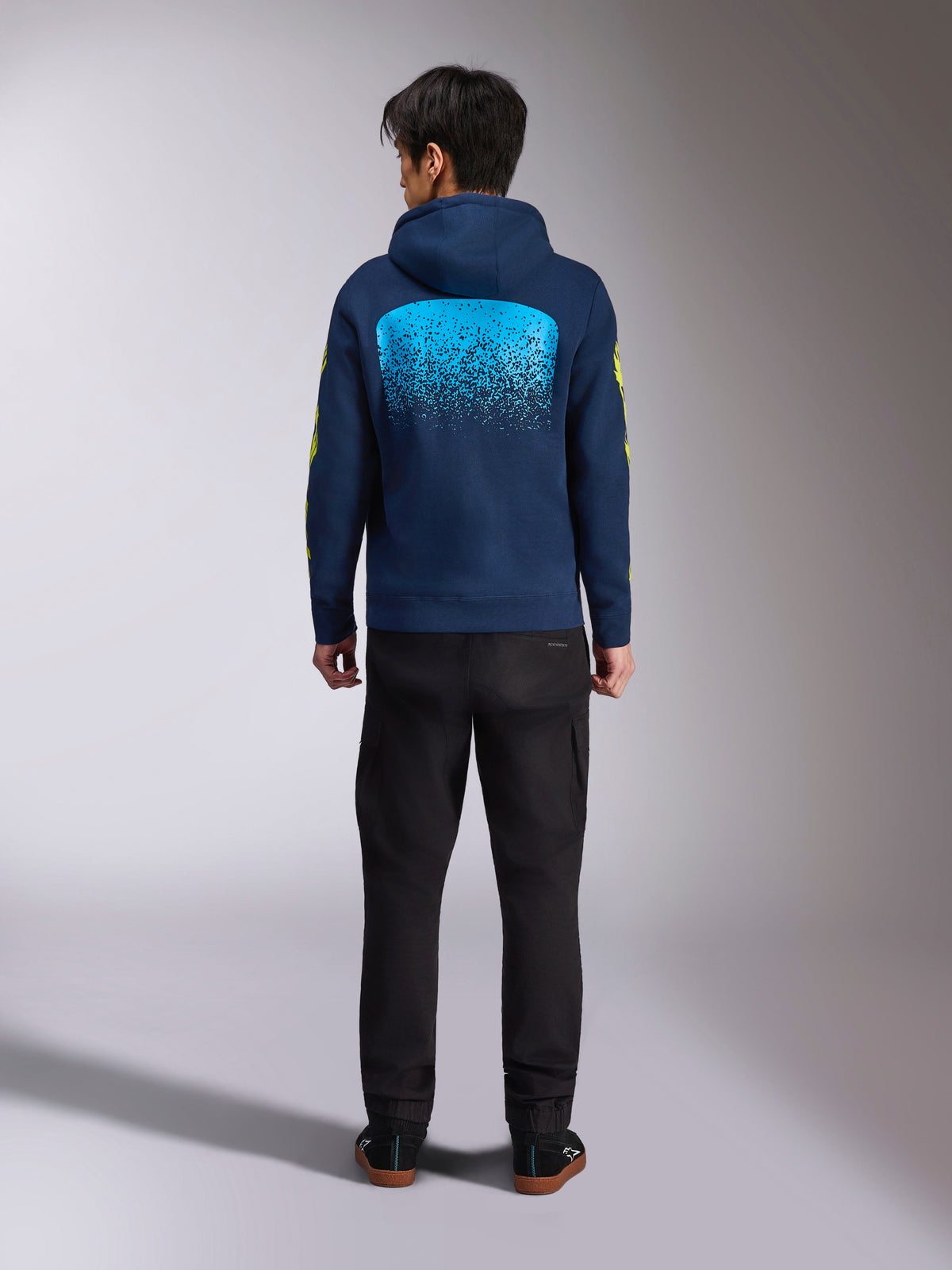 Sweat à capuche Alpinestars Obsessed bleu marine, vue de dos présentant un grand graphisme MX dégradé cyan et des logos jaunes sur les manches, polaire décontractée inspirée des sports mécaniques