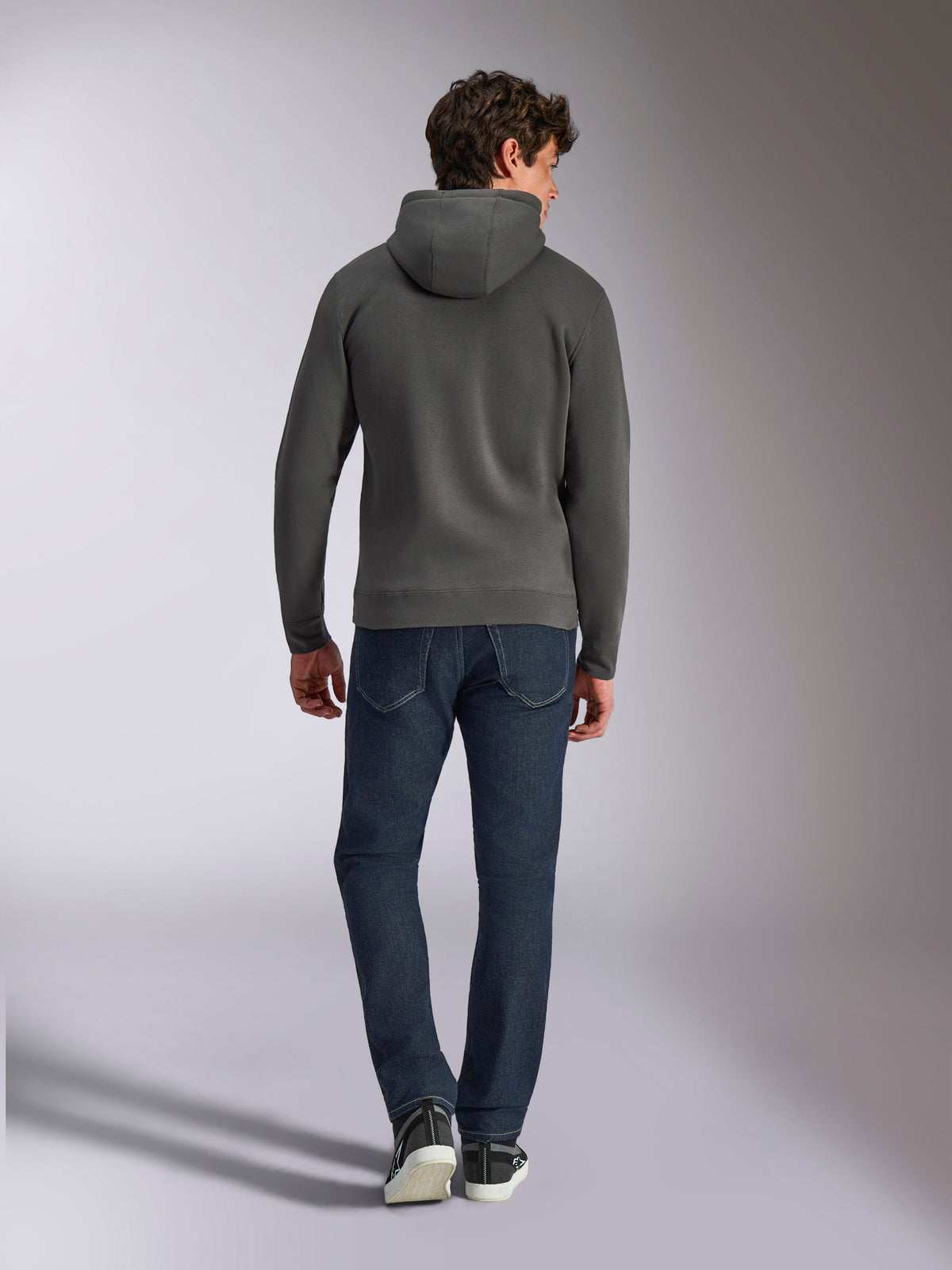 Sweat à capuche Alpinestars Ellipsoid, sweat à capuche gris anthracite, vue de dos, porté par un mannequin avec un jean foncé et des baskets noires, style streetwear décontracté inspiré du sport automobile