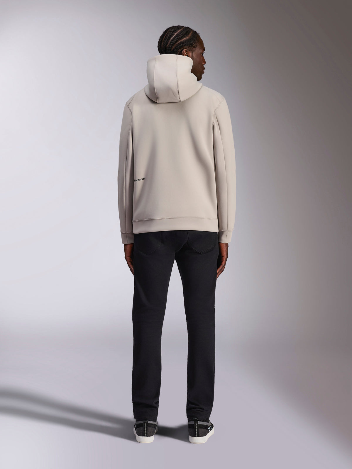 Sweat à capuche Alpinestars Cypher, gris clair Cement, vue arrière d'un homme portant un sweat à capuche en polaire entièrement zippé avec capuche à col haut et marquage Alpinestars à l'arrière, style streetwear décontracté inspiré du sport automobile associé à un pantalon noir