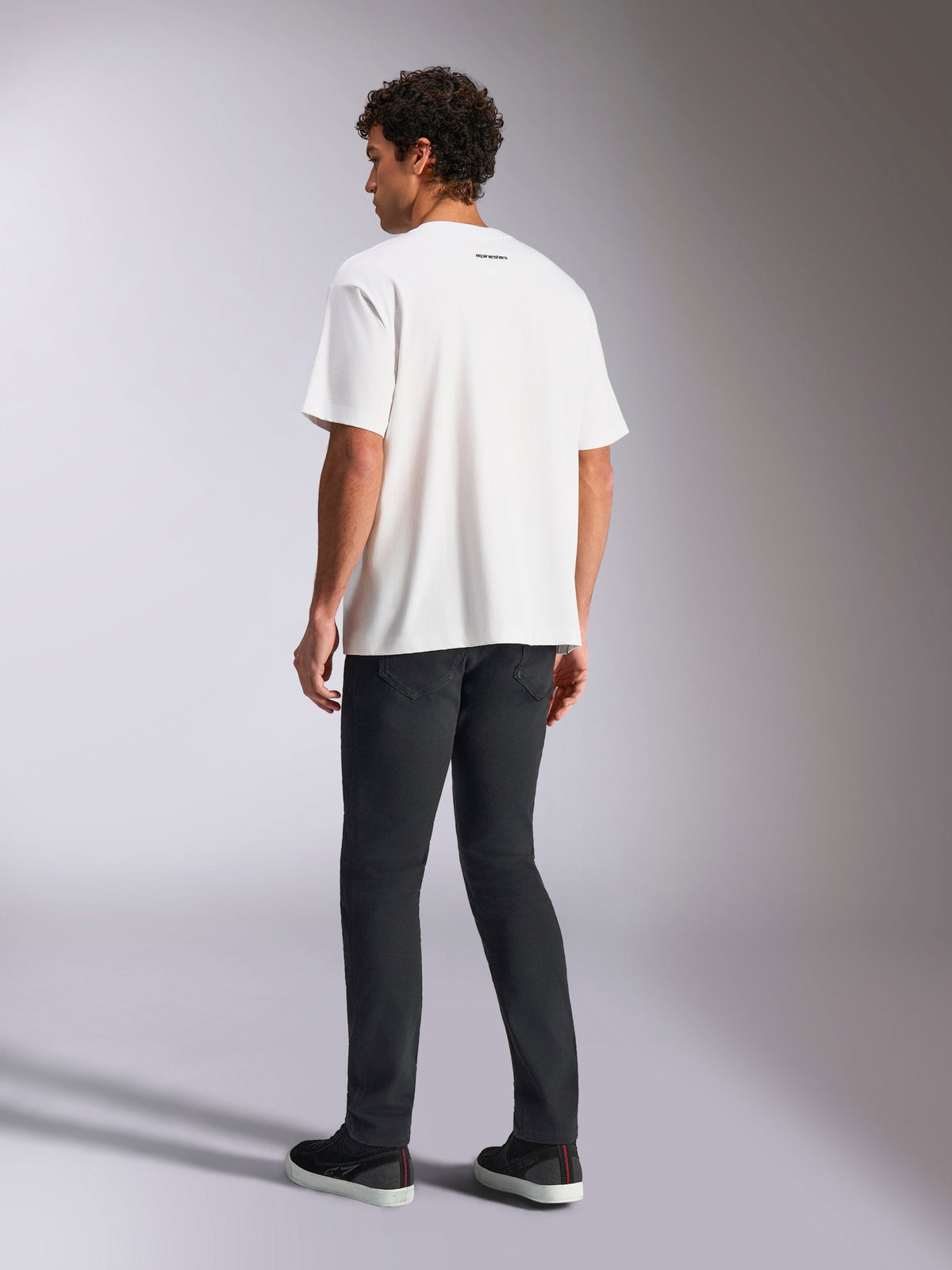 Alpinestars Focused Oversized CSF Tee, Short Sleeve T-Shirt, White, small black Alpinestars word logo on back neck, worn with black pants, oversized fit, casual motorsport-inspired streetwear