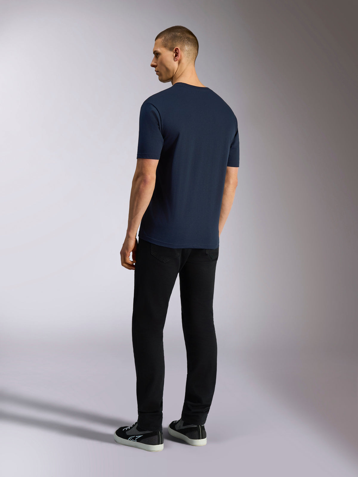 Alpinestars Noka CSF Tee, t-shirt à manches courtes, bleu marine, vue de dos sur un mannequin portant un pantalon noir et des baskets, style streetwear motorsport décontracté