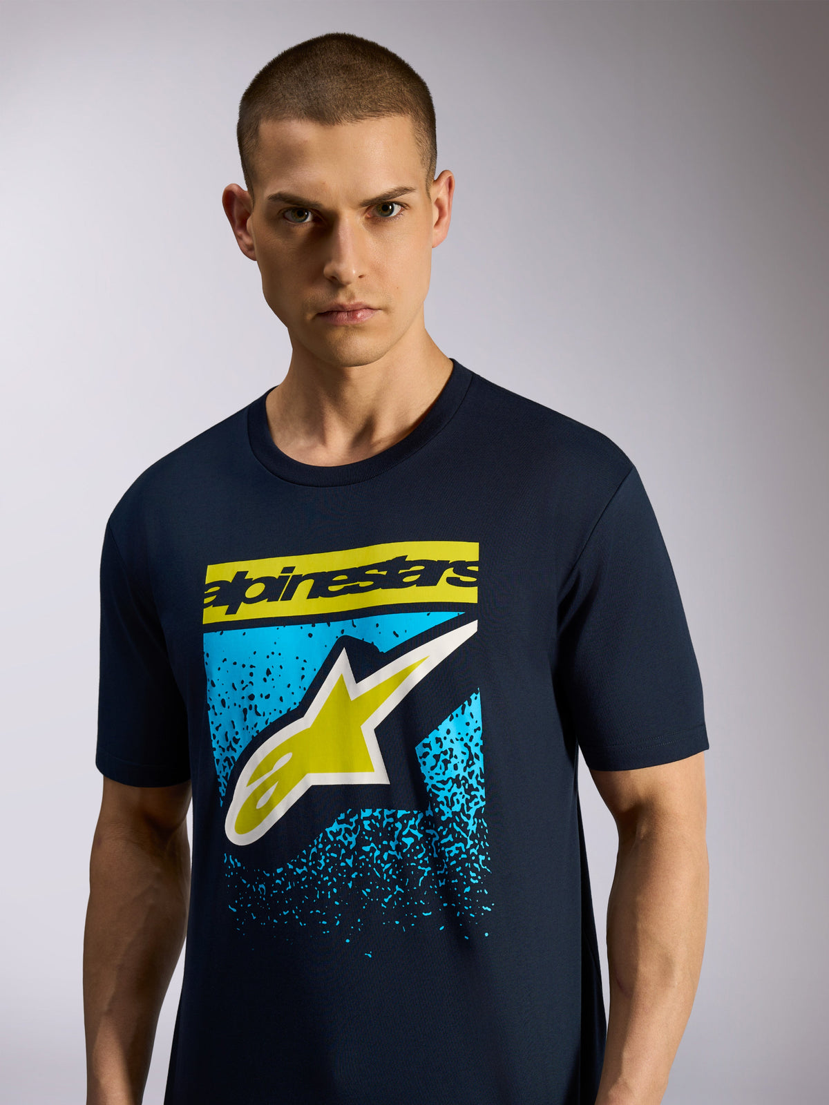 Alpinestars Noka CSF Tee, t-shirt à manches courtes, bleu marine, logo Astars à l'avant avec lettrage jaune et motif moucheté bleu, sportswear motorsport décontracté