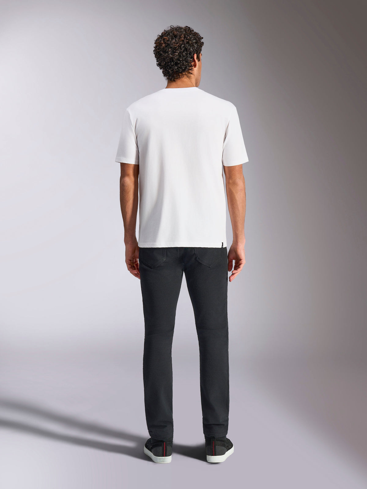 T-shirt Plate CSF Alpinestars, t-shirt à manches courtes, blanc, vue de dos sur modèle, associé à un pantalon noir, style streetwear décontracté inspiré du sport automobile