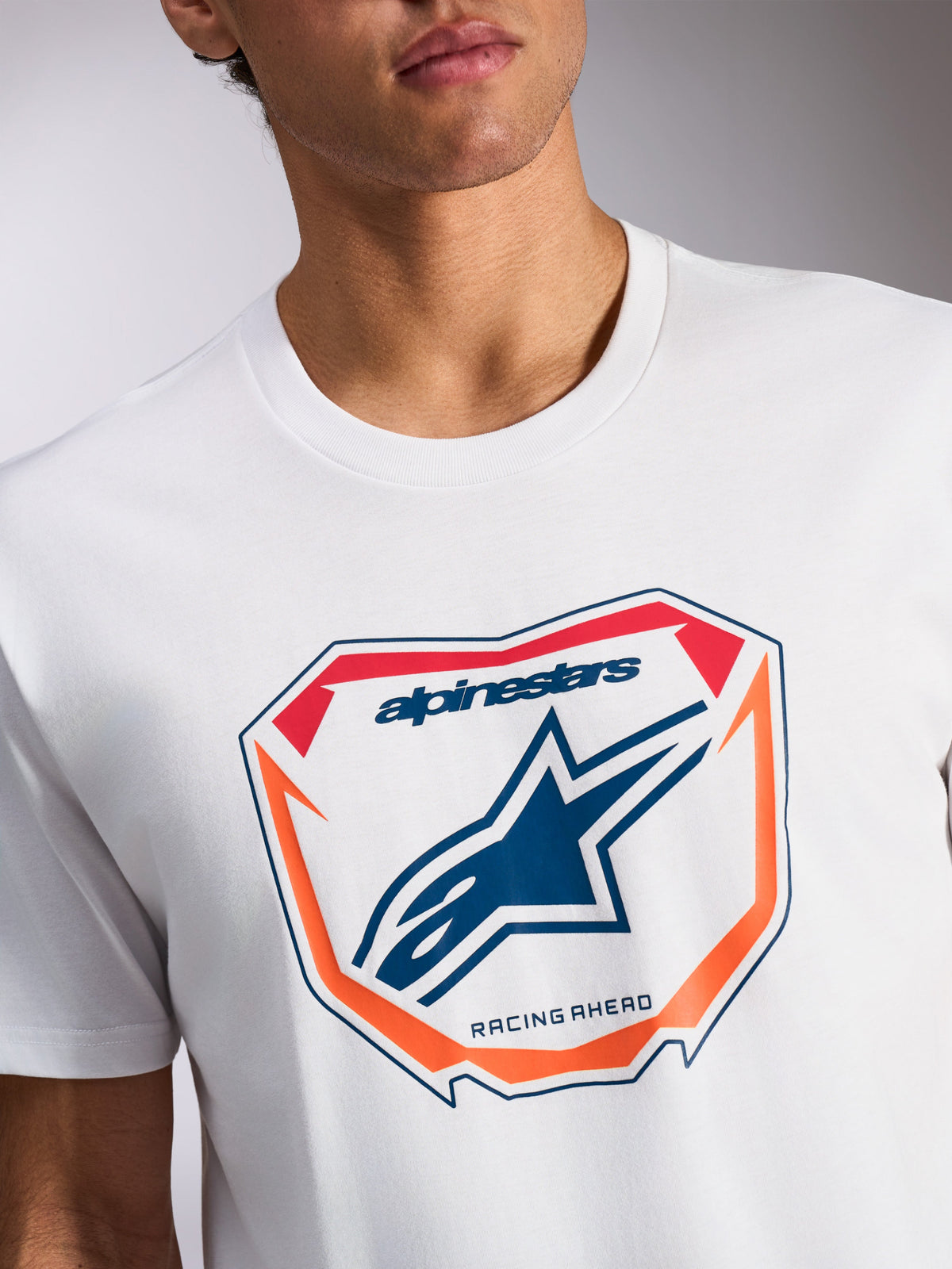 T-shirt Alpinestars Plate CSF, t-shirt à manches courtes, blanc, graphique de plaque MX à l'avant avec logo Astars bleu et texte « Racing Ahead », accents orange et rouges, sportswear décontracté
