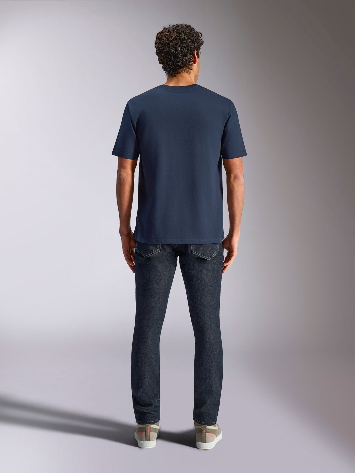 Alpinestars Trifecta CSF Tee, t-shirt à manches courtes, bleu marine, vue de dos sur mannequin, porté avec un jean en denim foncé et des baskets décontractées, streetwear motorsport décontracté