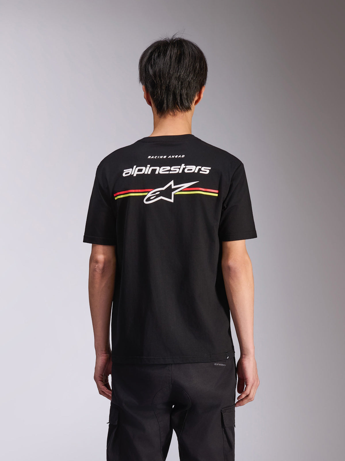 Alpinestars Lanes CSF Tee, t-shirt à manches courtes, noir, vue de dos présentant le logo Alpinestars blanc et l'étoile Astars avec des rayures rouges et jaunes, style streetwear décontracté motorsport