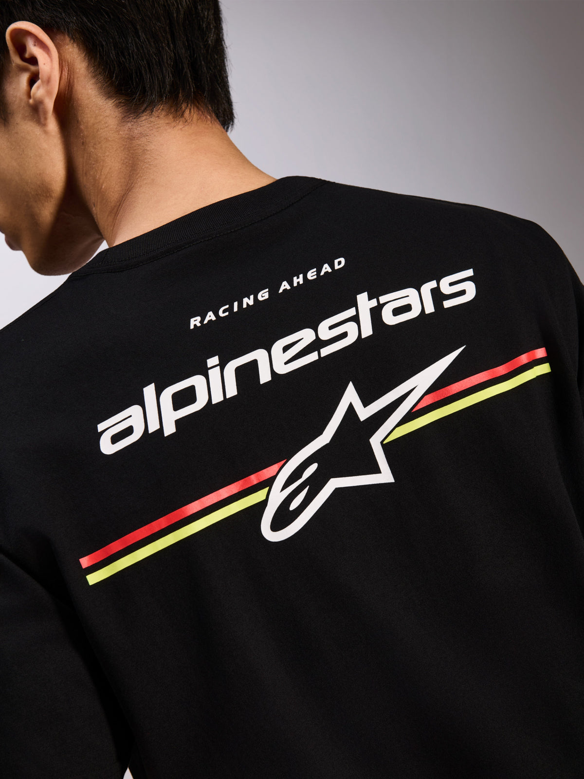Alpinestars Lanes CSF Tee, t-shirt noir à manches courtes, graphique au dos avec logos Alpinestars et Astars blancs sur rayures rouges et jaunes, streetwear décontracté inspiré du sport automobile