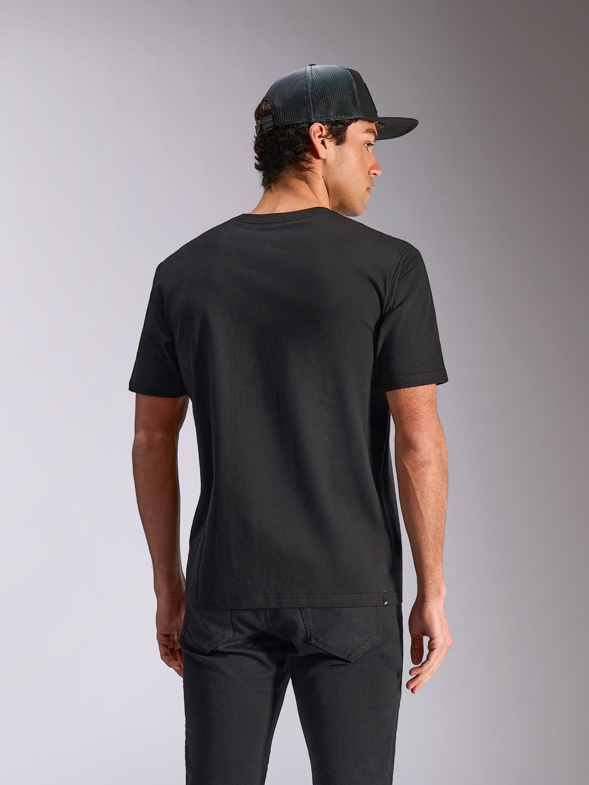 Alpinestars Verdure Camo CSF Tee, t-shirt à manches courtes, noir, vue de dos, porté avec une casquette à filet et un pantalon noir, streetwear motorsport décontracté