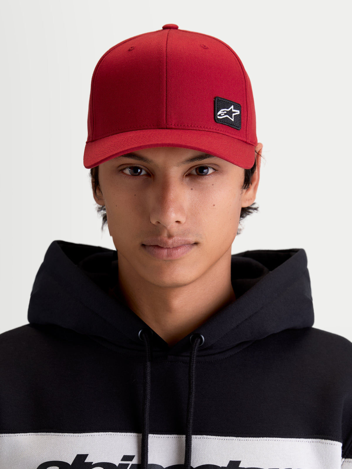 Alpinestars casquette Pivot, casquette de sportswear unisexe, rouge, vue de face sur modèle avec patch logo Astars brodé, visière courbée, couronne structurée et construction en sergé durable