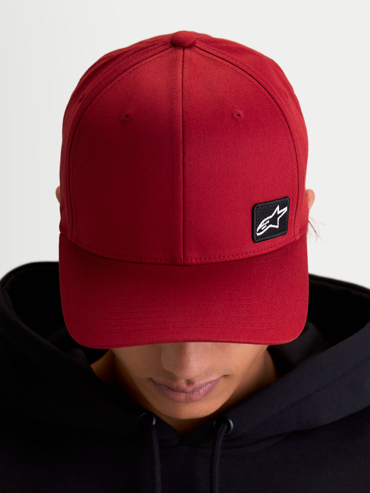 Alpinestars Pivot, casquette de sportswear unisexe, rouge foncé, avec visière courbée, couronne structurée et petit patch noir brodé du logo Astars, en tissu sergé durable, vue sur modèle