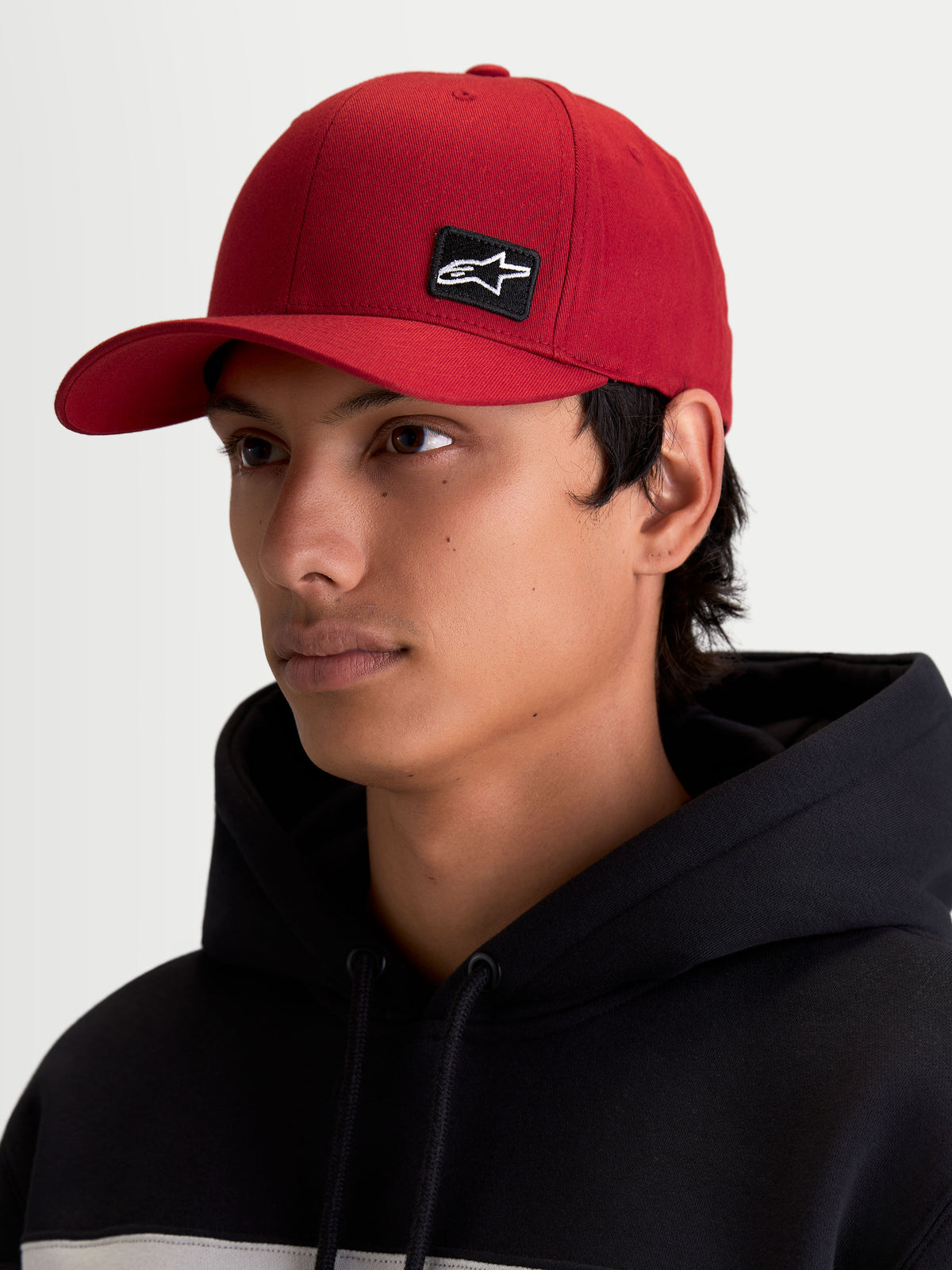 Alpinestars Casquette Pivot, casquette sportswear lifestyle unisexe, rouge, avec visière courbée et couronne structurée, petit patch logo Astars brodé noir, vue sur modèle.