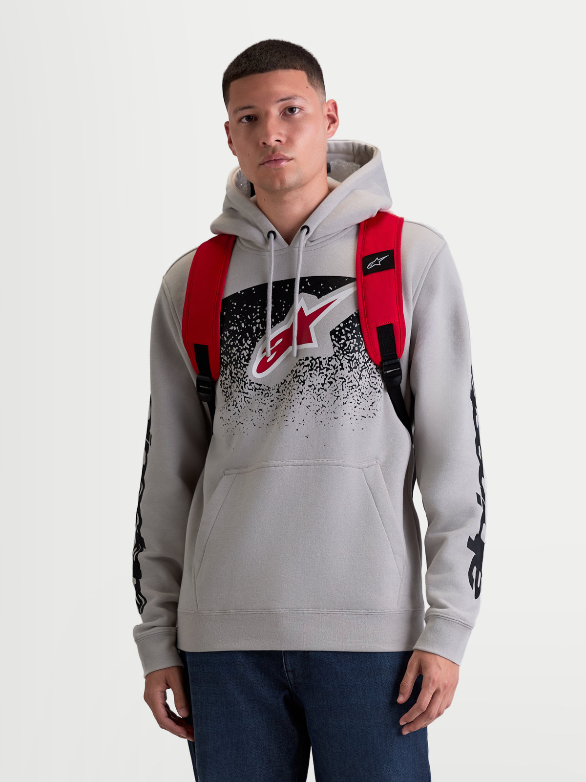 Alpinestars GFX Boss, sac à dos de sportswear urbain pour homme et femme, 20L, rouge et noir, polyester 600D durable, vue de face sur modèle avec bretelles ajustables en maille aérée et marquage en silicone en relief