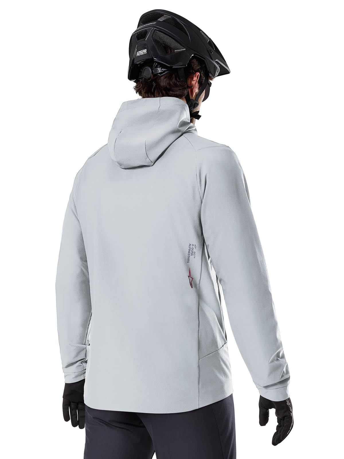 Veste thermique Alpinestars A-Dura, Gris Titanium, vue de dos d'un cycliste portant la veste isolante à capuche, associée à un casque de VTT noir et des gants noirs, avec un petit logo Alpinestars en bas du dos, conçue pour le VTT par temps froid.