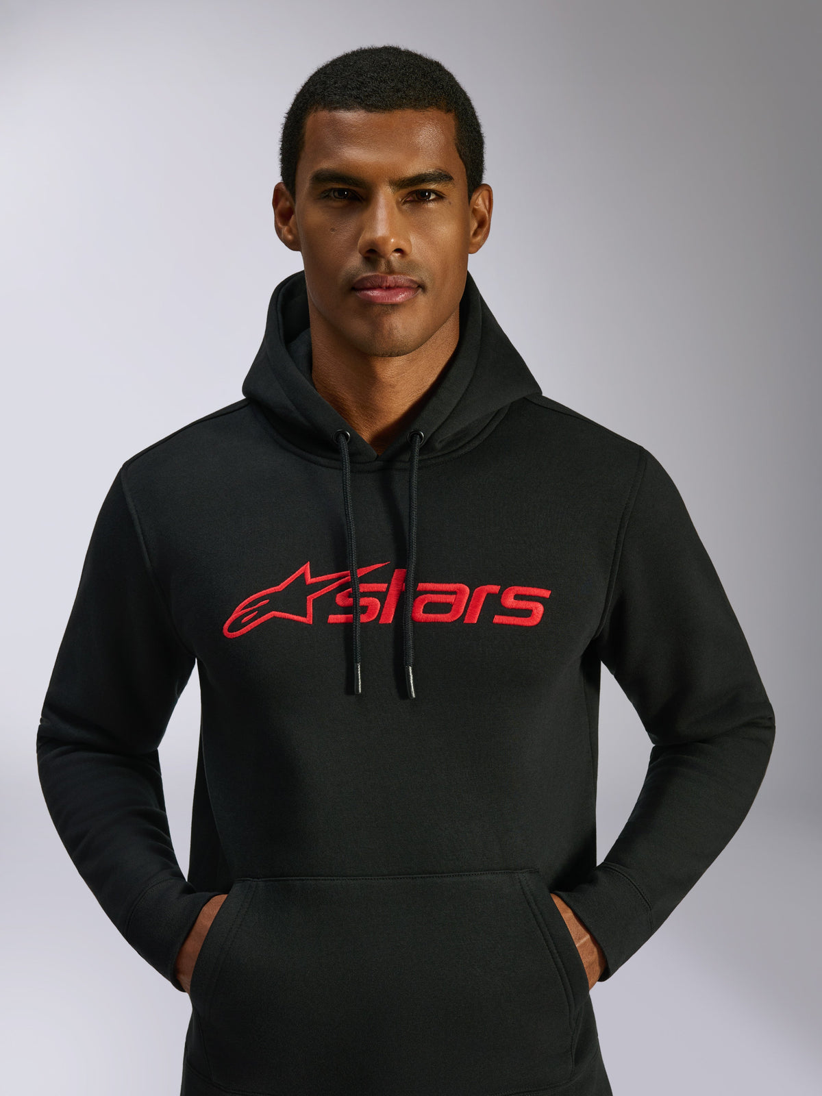 Alpinestars Blaze V3 Hoodie, casual streetwear, black with red Alpinestars logo on the chest, worn by a man, drawstring hood, long sleeves, modern motorsport-inspired design