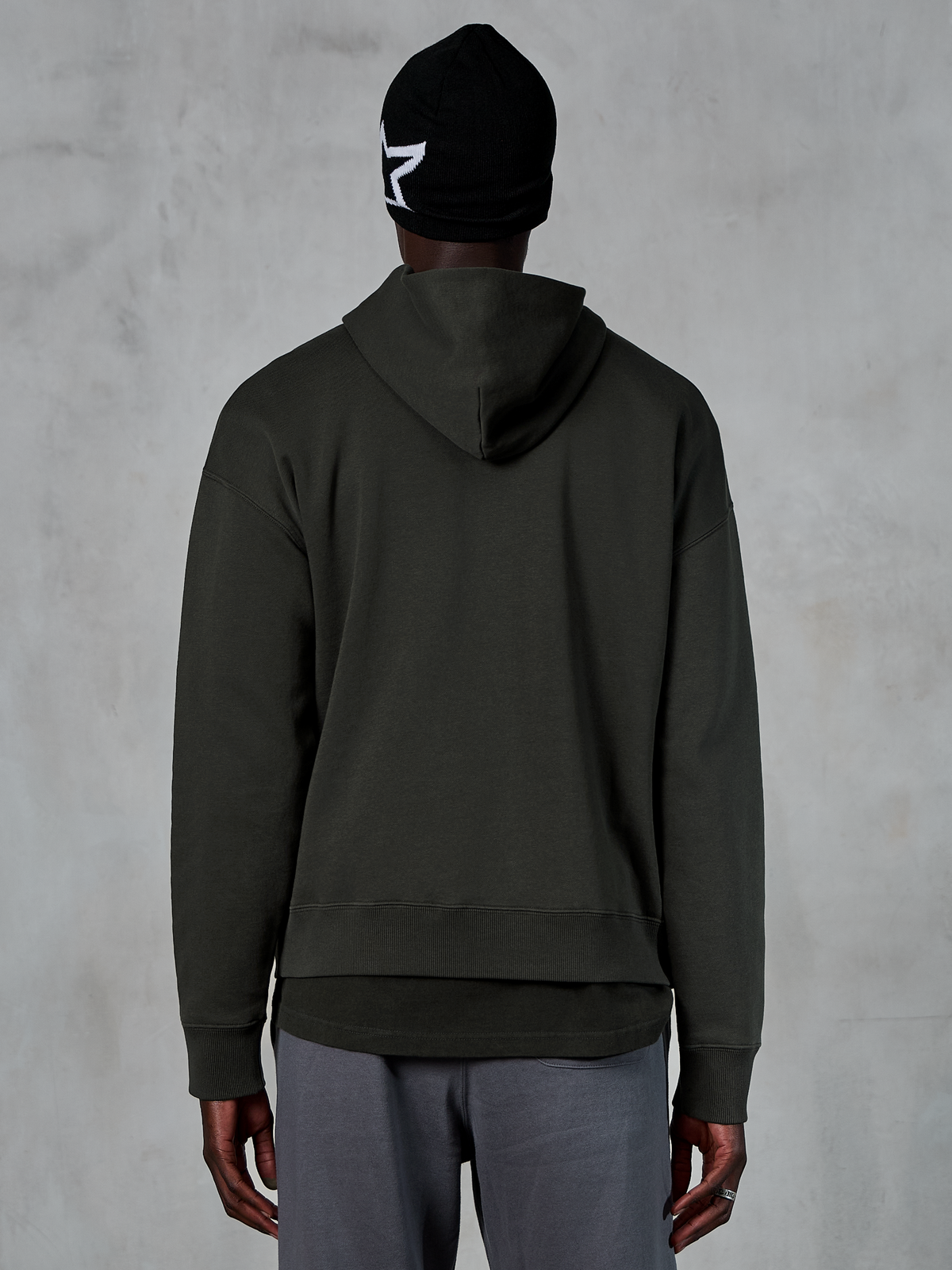 Sweat à capuche Alpinestars Essentials Ageless, vue de dos, Off Black, style streetwear décontracté, mannequin portant un bonnet noir avec logo étoile blanc et un pantalon gris, molleton premium avec finition stone-wash