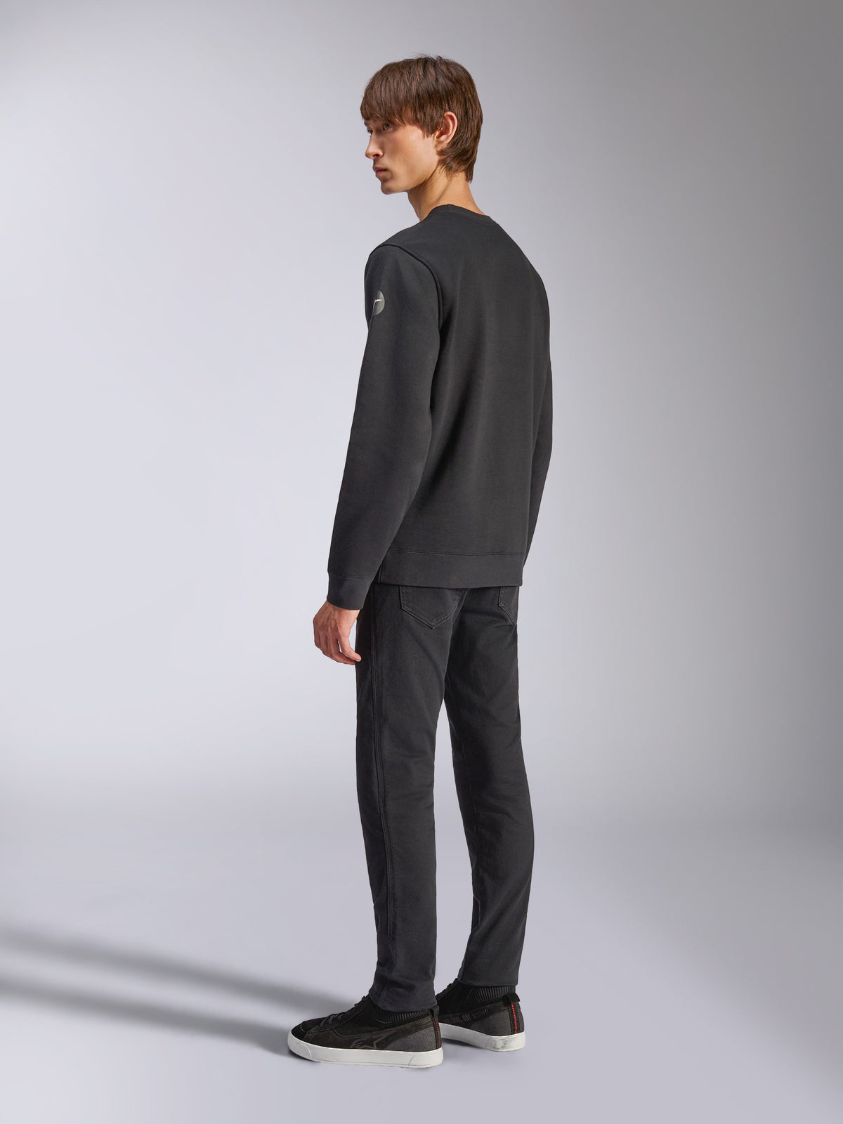 Alpinestars Bettern Crew, sweat en polaire, noir, modèle masculin vu de dos et de profil, avec poignets et ourlet côtelés et un petit logo sur la manche, streetwear décontracté d'inspiration sport mécanique
