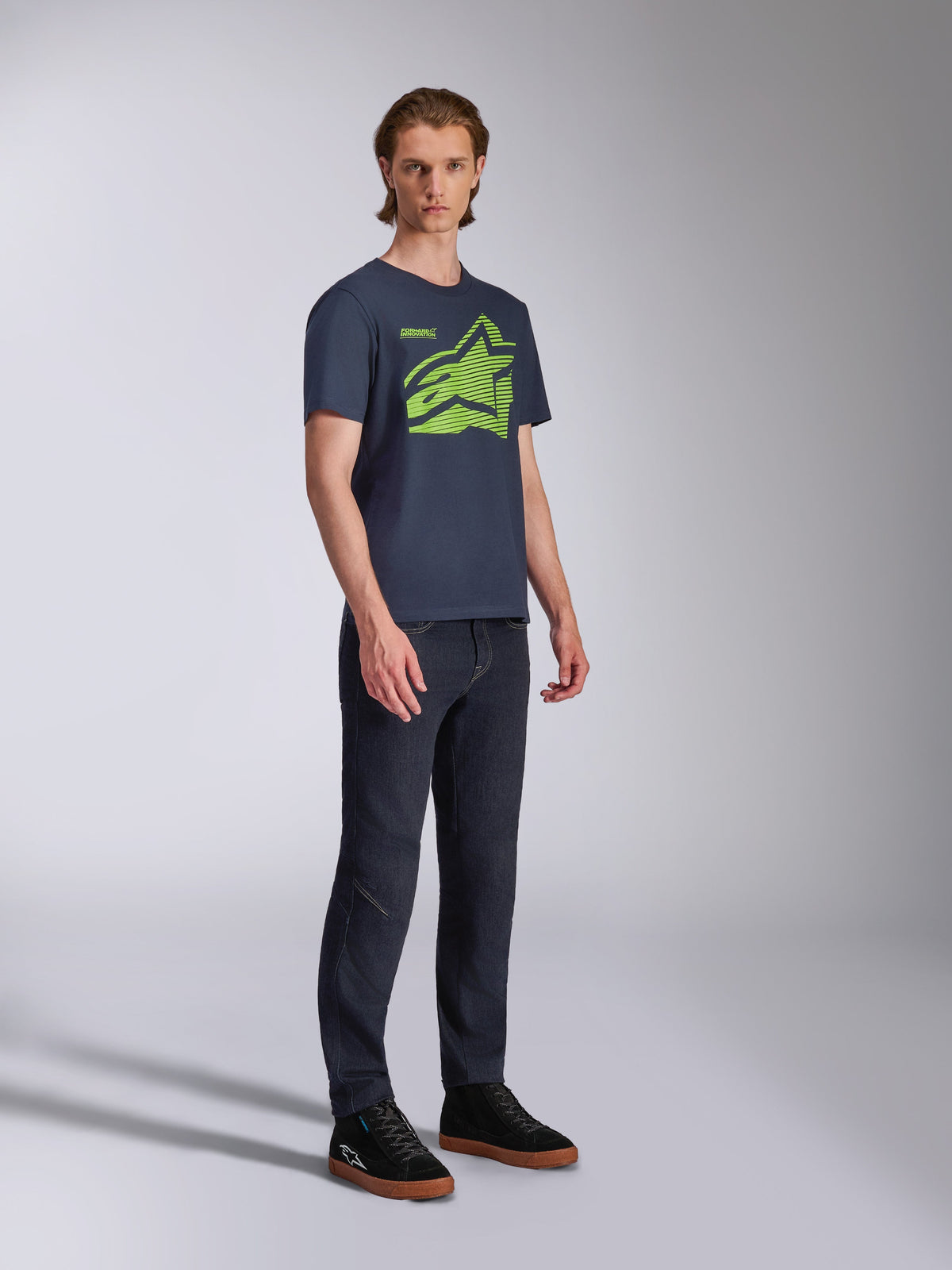 Alpinestars Fasting CSF Tee, t-shirt à manches courtes, bleu marine, logo Astars géométrique vert citron, porté avec un jean foncé et des baskets noires, streetwear de sport automobile décontracté