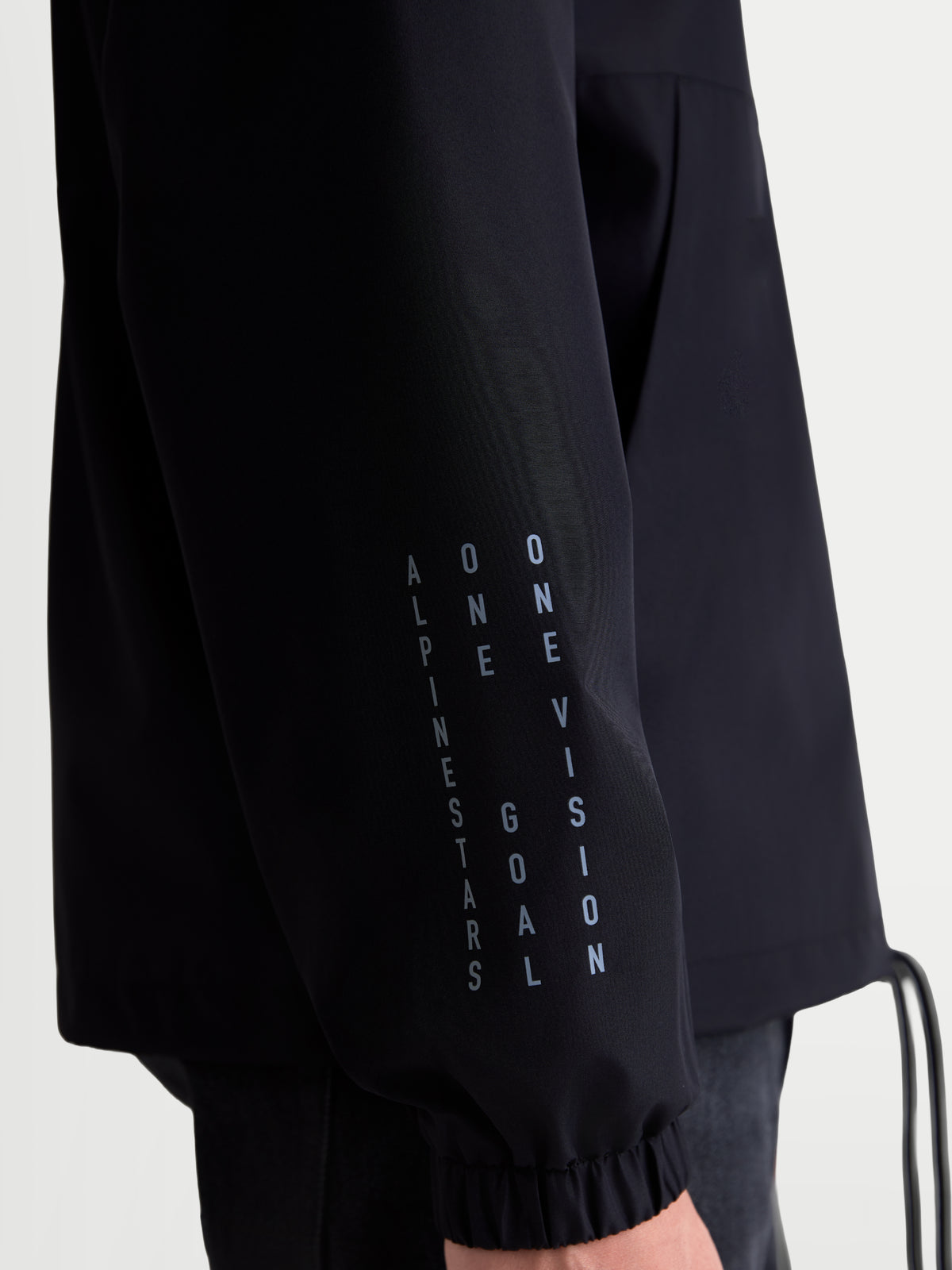 Alpinestars Speeder Resolve, veste coupe-vent légère de style sportswear, noire, vue rapprochée de la manche avec marquage vertical et poignet élastique, construction en polyester pour usage urbain.