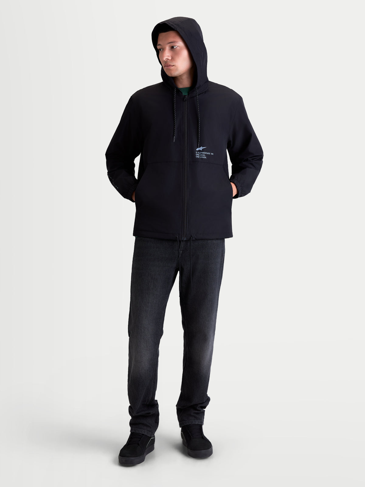 Alpinestars veste coupe-vent Speeder Resolve, vêtement sportswear léger pour homme pour usage urbain, noire, 100 % polyester. Vue sur mannequin en pied montrant la veste à capuche avec intérieur doublé en mesh et marquage Alpinestars sur la poitrine, parfaite pour un style décontracté au quotidien.