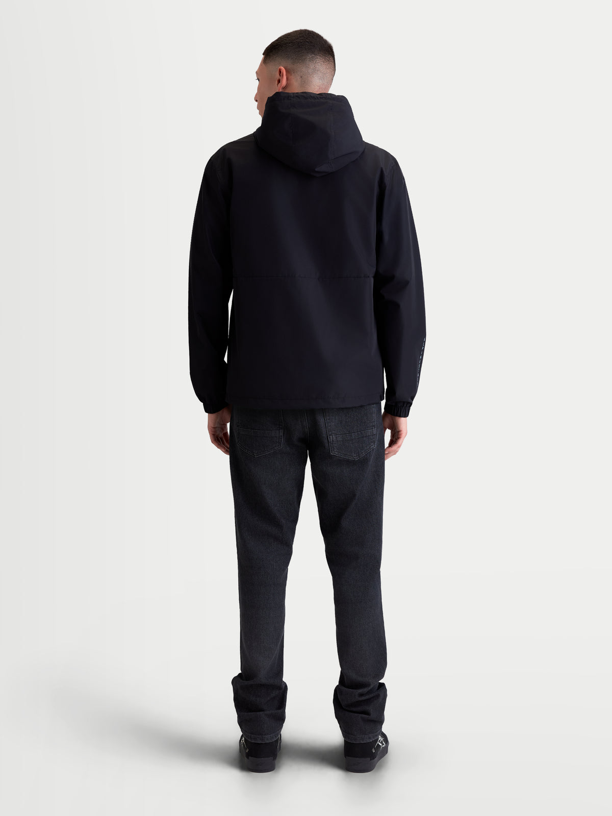 Alpinestars Speeder Resolve, veste coupe-vent pour usage urbain, noire, vue de dos sur modèle, vêtement sportswear léger avec capuche réglable et doublure en mesh respirante, style inspiré du motorsport.