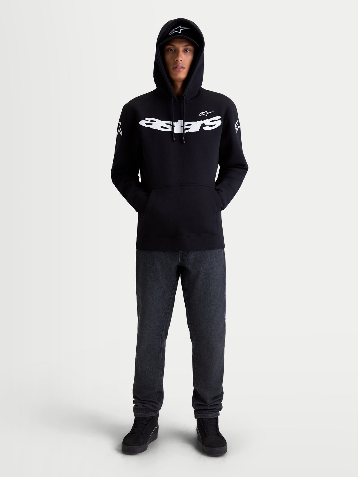 Alpinestars Sweat À Capuche Velocifier, sweat à capuche de sportswear, noir et blanc, mélange de coton et polyester recyclé, avec logo Astars sur la poitrine et logos sur les épaules, vu de face sur modèle pour un style décontracté hors moto