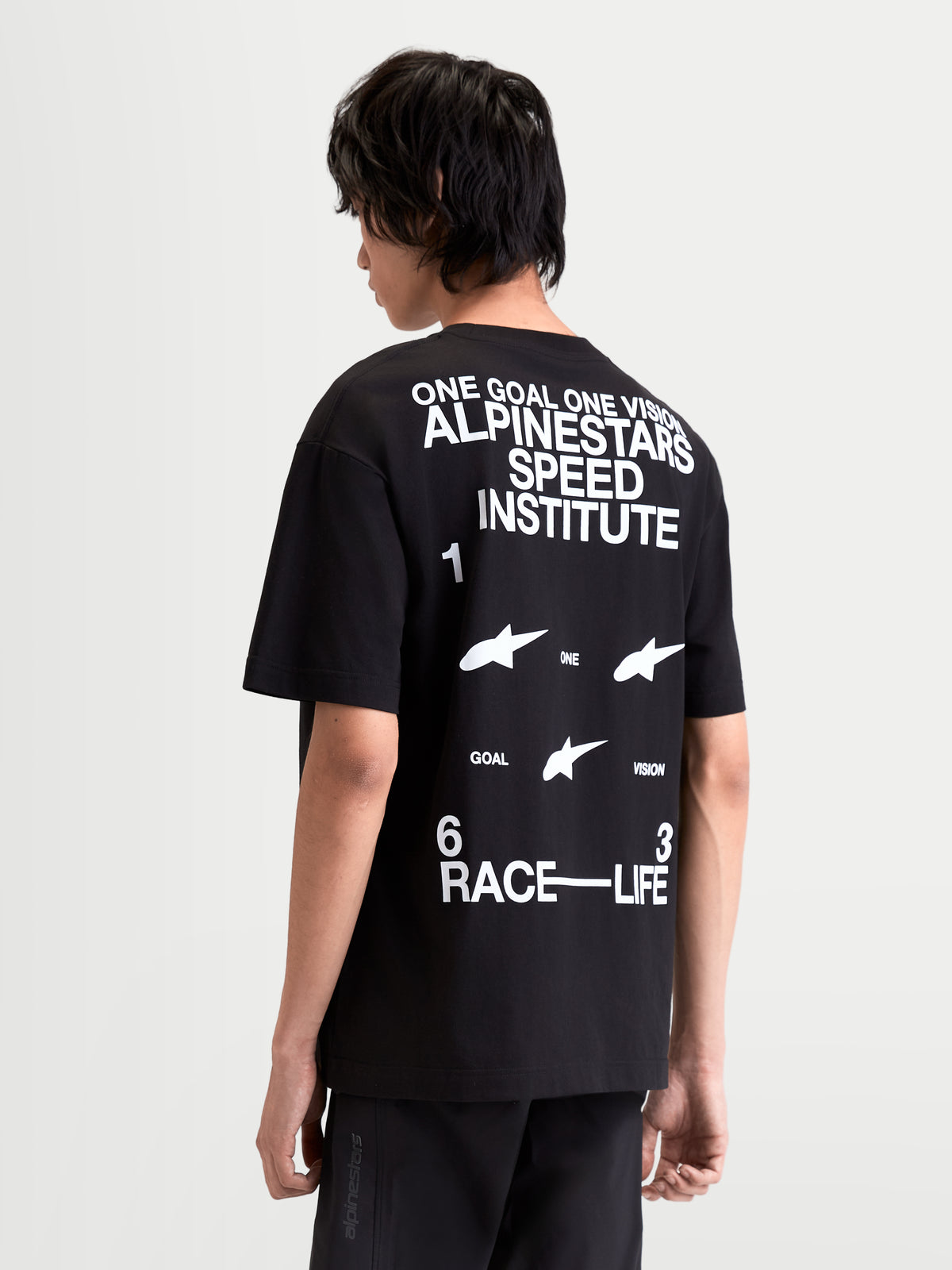Alpinestars T-Shirt Institute Oversized CSF, t-shirt de sportswear à manches courtes noir et blanc, vue de dos sur mannequin avec graphiques One Goal One Vision Alpinestars Speed Institute et Race-Life, coupe oversize décontractée.