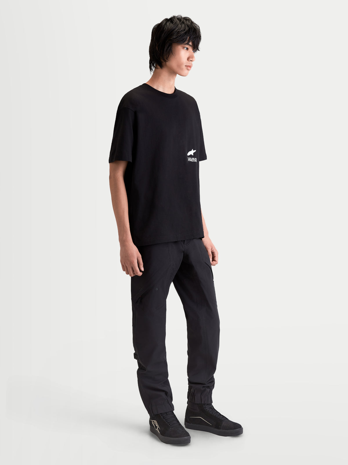 Alpinestars T-Shirt Institute Oversized CSF, t-shirt sportswear à manches courtes pour homme, noir et blanc, coupe oversize décontractée avec logo sur la poitrine, porté par un mannequin pour un style inspiré du motorsport.