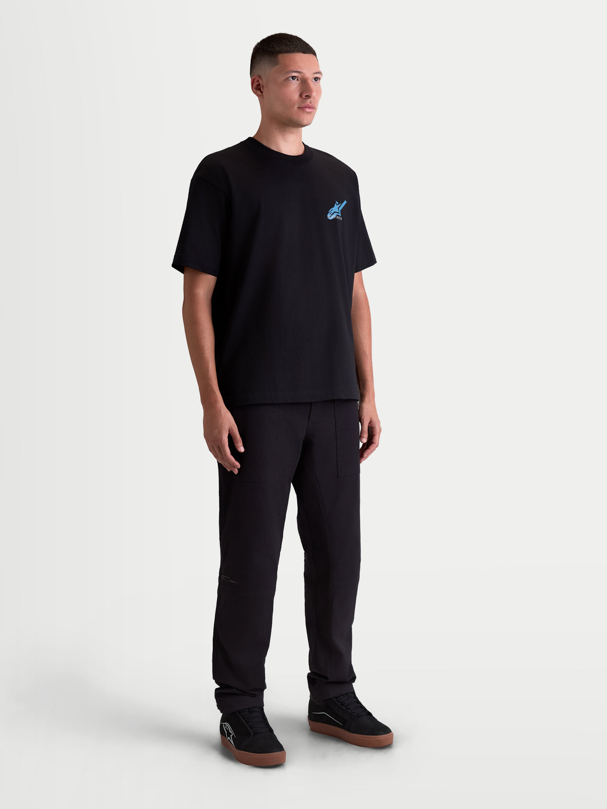 Alpinestars T-Shirt Ghost Oversized CSF, t-shirt de sportswear à manches courtes, noir avec logo graphique bleu, mélange de coton et polyester, coupe oversized décontractée, vue en pied sur modèle mettant en avant la silhouette large et le style motorsport.