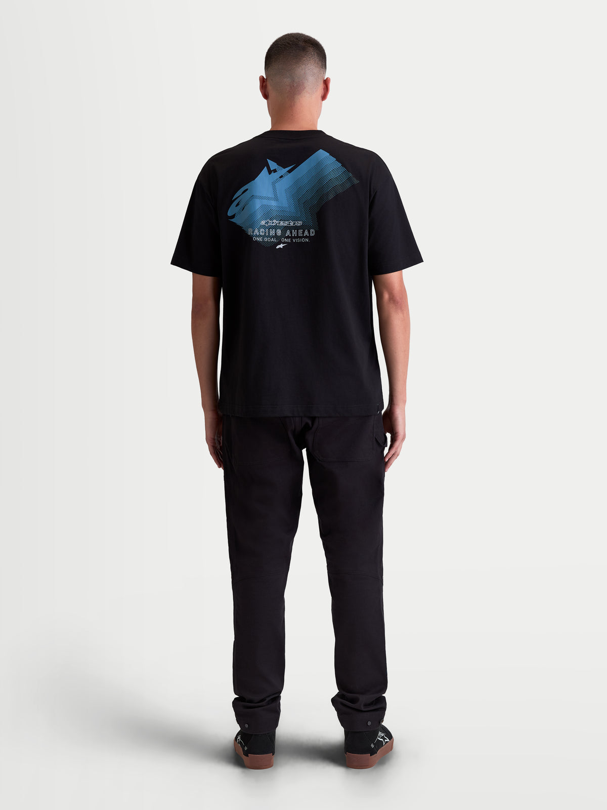 Alpinestars T-shirt Ghost Oversized CSF, t-shirt sportswear à manches courtes pour homme, noir et bleu, coupe oversized décontractée, graphique de logo dégradé bleu au dos avec texte 'Racing Ahead' et 'One Goal. One Vision.', vue de dos sur modèle