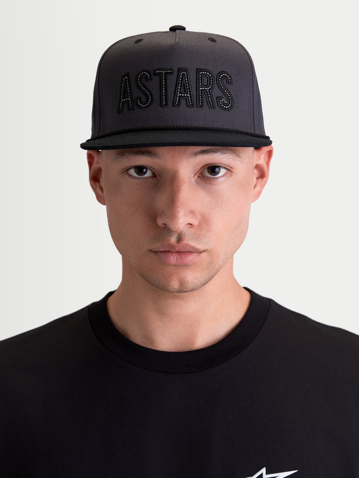 Alpinestars Stadium Snapback, casquette de sportswear lifestyle pour homme, gris foncé et noire, avec couronne structurée, visière plate et logo Astars appliqué sur le devant, portée par un modèle