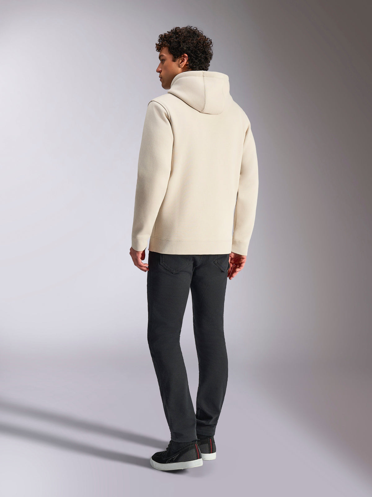 Sweat à capuche Alpinestars Always V3, blanc cassé, vue arrière d'un mannequin portant le sweat à capuche et un pantalon noir, streetwear décontracté inspiré du sport automobile, design minimaliste avec capuche et ourlet côtelé