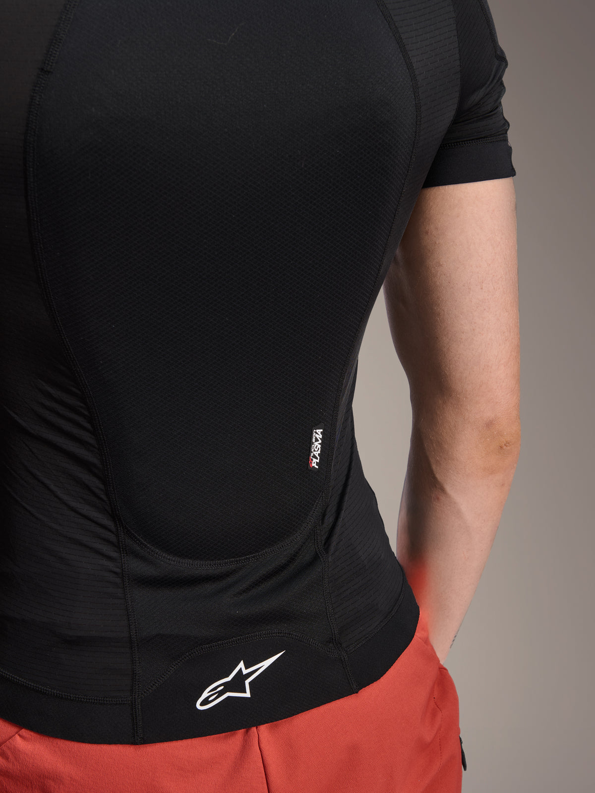 Veste de protection Alpinestars A-Motion Plasma - Manches courtes, Black Camo, vue arrière détaillée montrant le marquage Nucleon PLASMA et le logo Alpinestars blanc sur l'ourlet, construction en maille extensible respirante pour la protection VTT