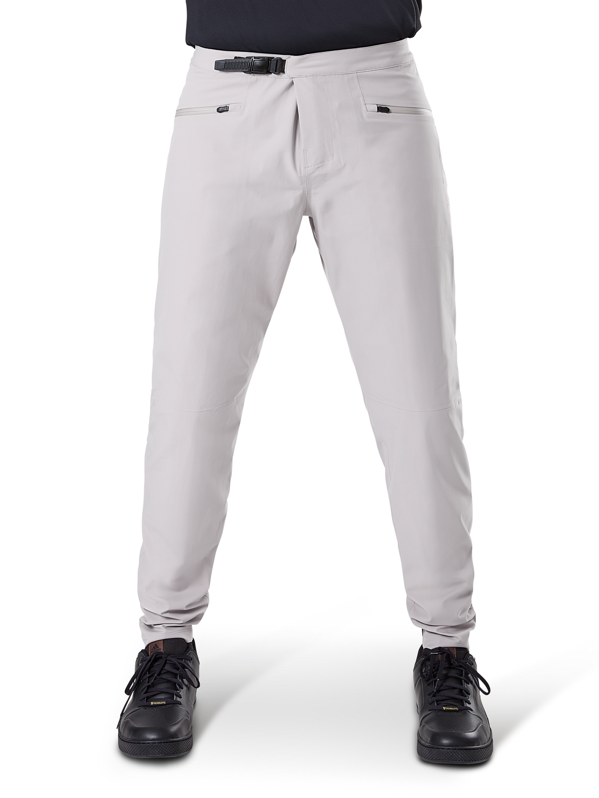 Pantalon imperméable Alpinestars A-Dura, pantalon de cyclisme VTT, Gris Titane, vue de face, avec fermeture à cliquet noire à la taille, deux poches zippées et chevilles élastiquées, porté avec des baskets noires, équipement technique imperméable pour le VTT
