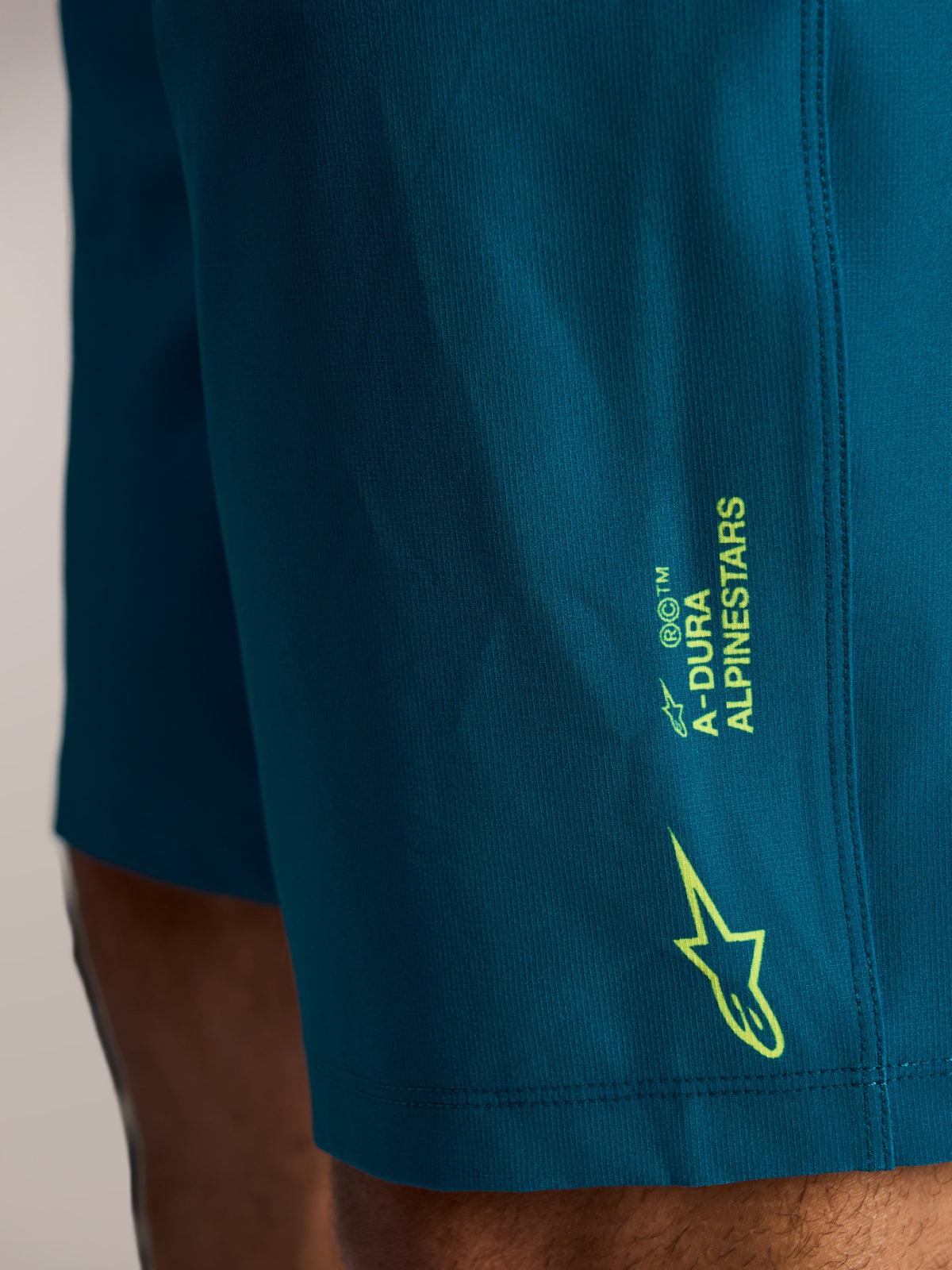 Short VTT A-Dura Ride bleu-vert, marquage latéral Alpinestars vert citron et logo étoile sur tissu extensible.