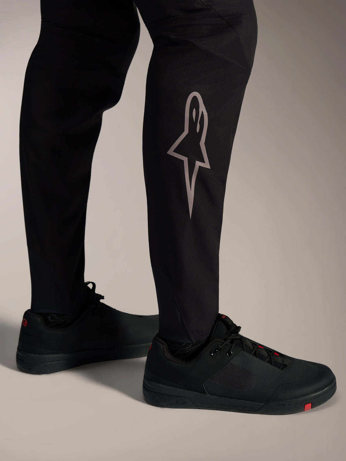 Pantalon VTT A-Supra Elite noir, logo Astars argenté sur le tibia, conçu pour le cyclisme haute performance.